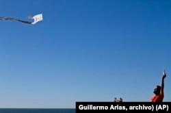 ARCHIVO - Dan Watman y un niño vuelan una cometa hecha de bolsas de plástico y periódicos, cerca de la división fronteriza entre Estados Unidos y México, en Tijuana.