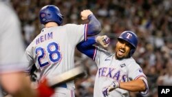 Marcus Semien (der.) festeja su jonrón de tres carreras junto a Jonah Heim, su compañero en los Rangers de Texas, en el cuarto juego de la Serie Mundial ante los Diamondbacks de Arizona. (AP Foto/Brynn Anderson)