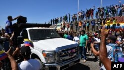 La gente aplaude mientras camiones con ayuda humanitaria a Venezuela se acercan a la frontera entre Brasil y Venezuela en Pacaraima, estado de Roraima, Brasil, el 23 de febrero de 2019.