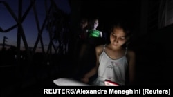 Emily Villega de 10 años hace la tarea con la luz de su celular.