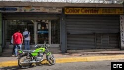 Un local comercial abierto y otro cerrado este viernes, 28 de octubre de 2016, en Caracas (Venezuela).