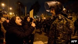 Una mujer iraní que asiste la noche del sábado a una vigilia en memoria de las víctimas del avión ucraniano le habla a un policía que vigila el área (Foto: Mona Hoobehfekr/AFP).