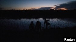 Un coyote ayuda a migrantes de Honduras a pasar junto a alambre de púas cargado a lo largo de la orilla del río Grande cuando ingresan a los Estados Unidos desde México en Eagle Pass, Texas, EE.UU., 14 de septiembre de 2023. REUTERS/ Adrees Latif