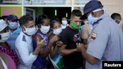 Un policía organiza una fila de personas que esperan para comprar alimentos en La Habana, el 3 de abril del 2020.