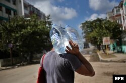 Un hombre camina con dos bidones de agua potable en uno de los barrios afectados por el paso del huracán Irma en La Habana.