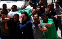 Dolientes cantan consignas islámicas mientras llevan el cuerpo de Awad Abu Selmiya, durante un funeral de trece militantes de Hamas frente a una mezquita en la ciudad de Gaza, el jueves 13 de mayo de 2021. Foto: AP/Adel Hana.