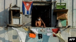 Un hombre con una máscara protectora desde su balcón en La Habana. (YAMIL LAGE / AFP)