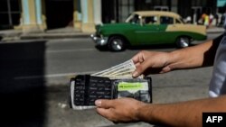 Un hombre muestra su cartera con dólares estadounidenses. (YAMIL LAGE/AFP/Archivo)