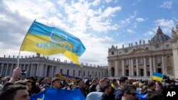 Fieles muestran banderas ucranianas durante la oración del mediodía del papa Francisco en la Plaza de San Pedro, en el Vaticano, el domingo 27 de febrero de 2022. (Foto AP/Gregorio Borgia)