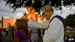 Un sacerdote bendice a un peregrino durante la procesión a El Rincón en adoración a San Lázaro. Yamil Lage/AFP