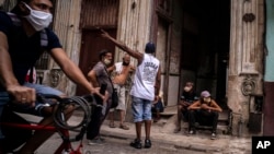 Residentes se reúnen en la acera, a la entrada de un edificio, en medio del calor intenso de estos días en La Habana. (AP/Ramon Espinosa)